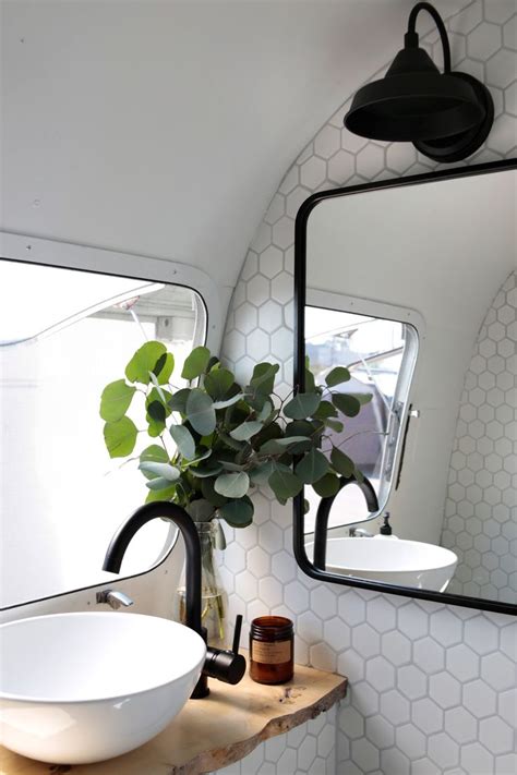 A White Sink Sitting Under A Bathroom Mirror Next To A Wooden Counter
