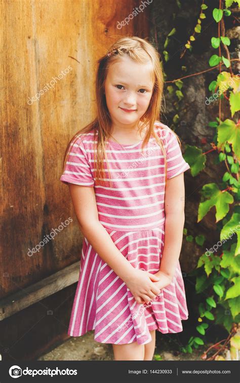 Outdoor Portrait Of Adorable 6 Year Old Girl Wearing Pink Stripe Dress