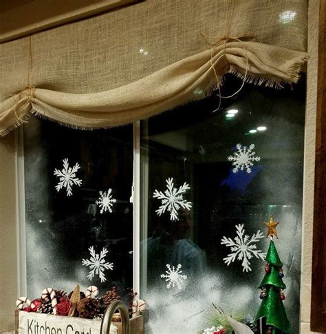 A Kitchen Window Decorated For Christmas With Snowflakes