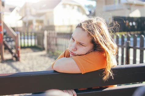 Sad Lonely Teenage Girl Sitting On Bench In The Playground Stock Photo