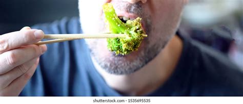 Man Puts Broccoli His Mouth Chopsticks Stock Photo 1535695535