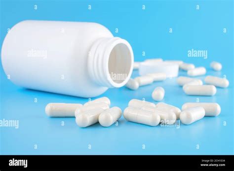 medication bottle and white pills spilled over blue colored background medication and