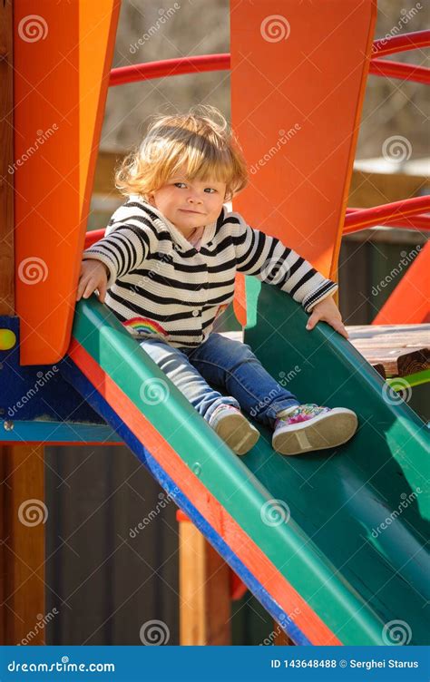 Cute Little Toddler Girl Sliding Down The Children`s Slide Stock Photo
