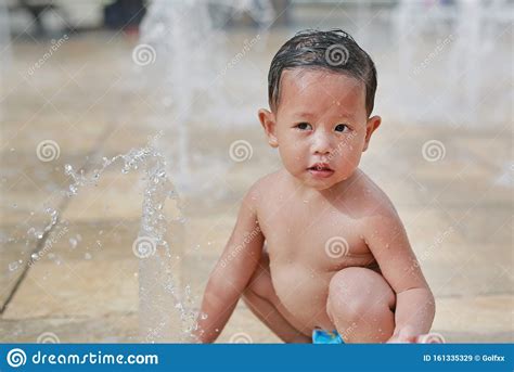Adorable Little Asian Baby Boy Having Fun On Water Stream Of A