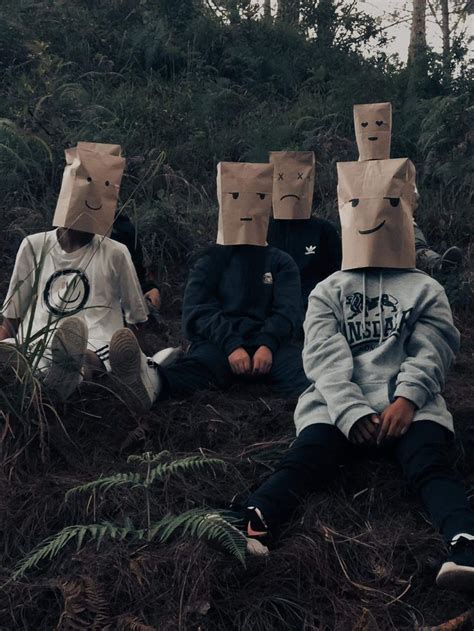 Four People With Paper Bags On Their Heads Sitting In The Grass