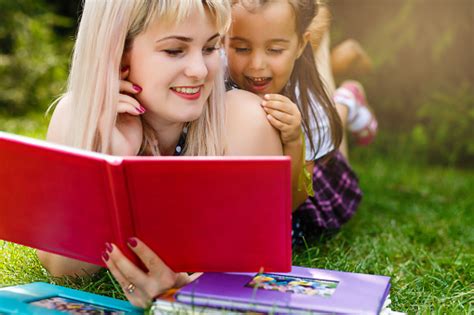 Ibu Muda Yang Cantik Membaca Buku Untuk Putri Kecilnya Di Padang Rumput