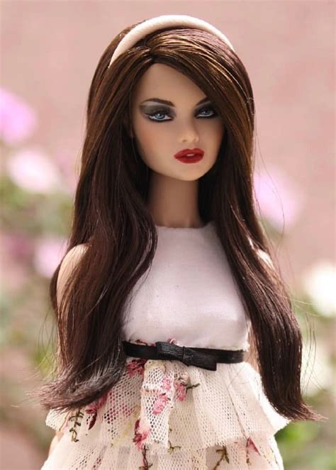 a doll with long brown hair wearing a white dress