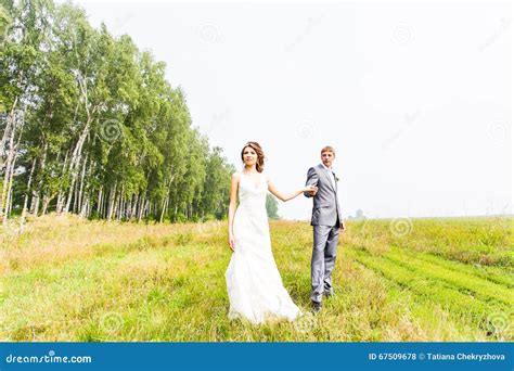 Young Couple In Love Bride And Groom Posing In A Field With Yellow
