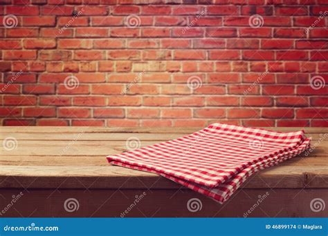 Wooden Table With Red Checked Tablecloth Over Brick Wall Stock Photo