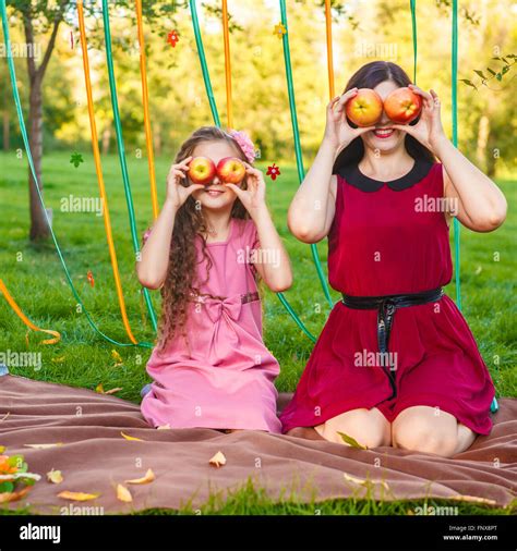 Mom And Daughter In The Park Posing With Apples In Their Hands Stock