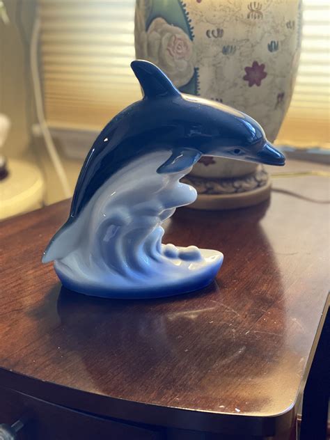 A Dolphin Figurine Sitting On Top Of A Wooden Table