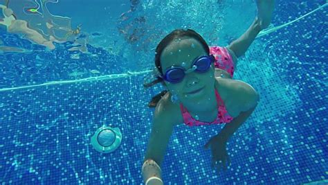 A Young Girl Swims Towards The Camera While Underwater In A Pool Stock