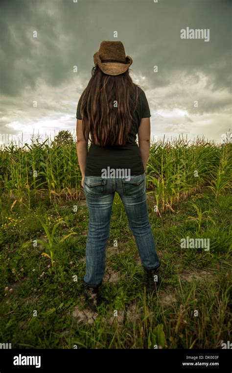 A Woman With Back Turned Is Looking Out Towards A Corn Field With A