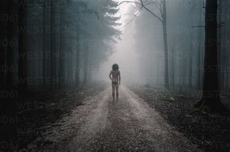 Rear View Of Nude Man Standing On Path In Foggy Forest Stock Photo