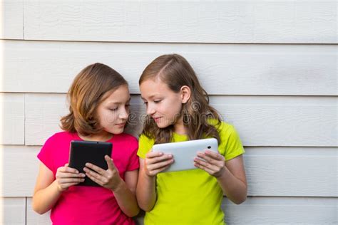 Twin Sister Girls Playing With Tablet Pc Happy On White Wall Stock