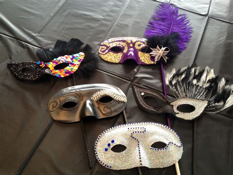 Several Masquerade Masks On A Table With Purple And Black Feathers In