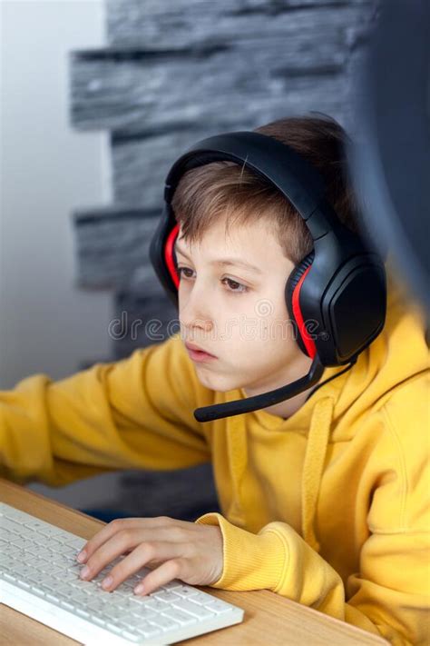 Teenage Boy In Headphones Uses Computer At Home At A Distance Learning