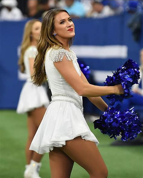 The Cheerleader Is Dressed In All White And Has Blue Pom Poms On Her Legs