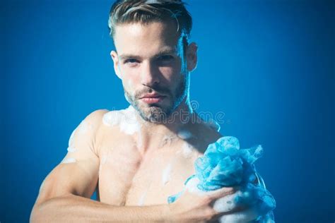 smiling man washing body with moisturizing gel and washcloth taking shower morning routine spa
