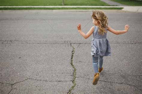Back View Of Young Girl Running Across The Street Stock Photo Offset
