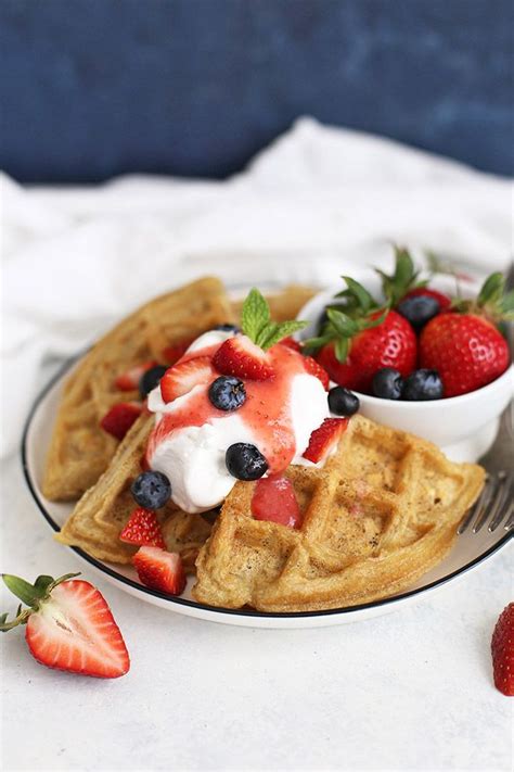 A Plate With Waffles Strawberries And Whipped Cream On It Next To A