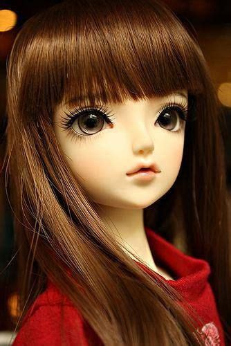 A Doll With Long Brown Hair Wearing A Red Hoodie And Black Eyeliners