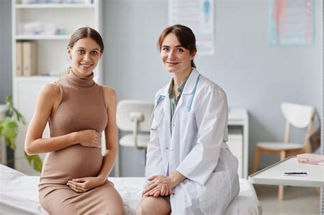premium photo portrait of pregnant woman and her gynecologist smiling at camera together while