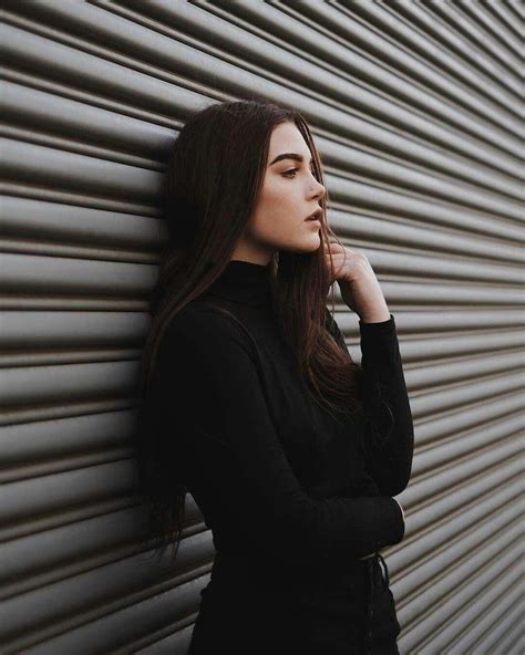 A Woman Leaning Against A Metal Wall With Her Hand On Her Chin And