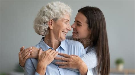 Smiling Adult Daughter And Senior Mother Hug At Home Stock Image