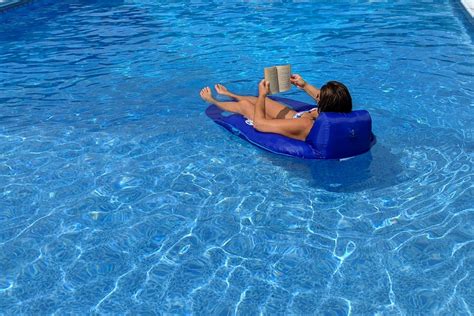 Woman On A Blue Float Reading A Book In A Swimming Pool Real People