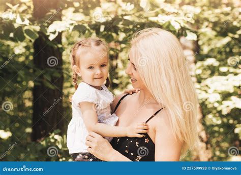 Mamá Sostiene En Sus Brazos Y Abraza A Una Niña Pequeña Foto De Archivo