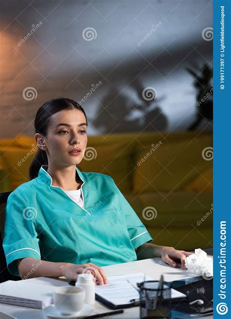 nurse in uniform sitting at table and looking away during night shift stock image image of