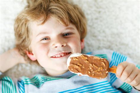 Little Blond Kid Boy With Curly Hairs Eating Ice Cream Popsicle With