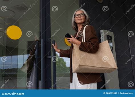 60 year old well groomed slender gray haired business woman dressed stylishly walks around the
