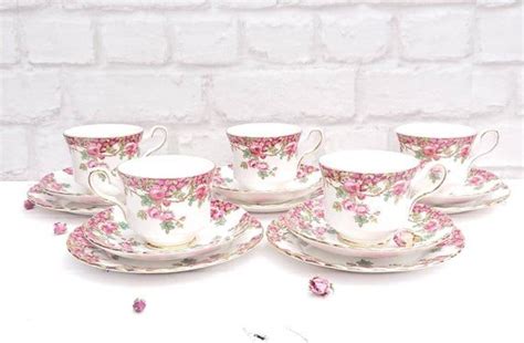 Five Tea Cups And Saucers With Pink Flowers On Them Sitting Next To