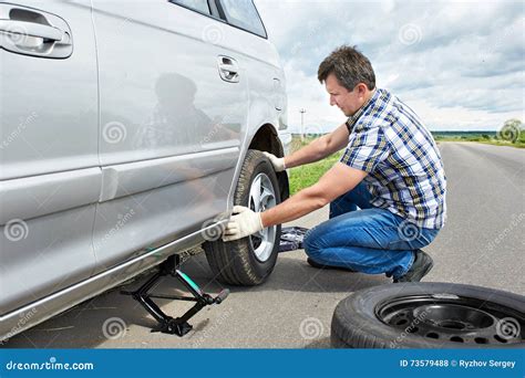 Man With Jack Changing A Spare Tire Of Car Stock Photo Image Of Driver Manual