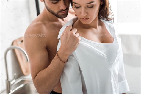 Muscular Man Undressing Brunette Pretty Girl With Closed Eyes Stock