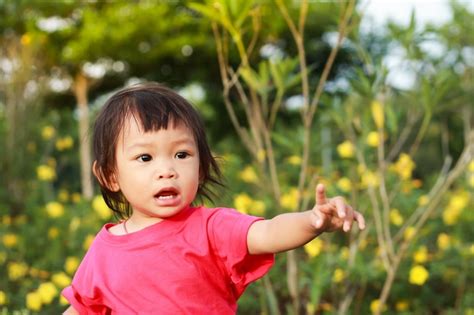 Una Niña Niño Apuntando Con Su Dedo A La Izquierda En El Jardín Foto