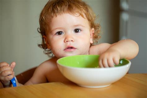 Funny Baby Eating Food Himself With A Spoon On Kitchen Child Nutrition