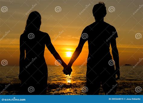 Couple Silhouette Holding Hands At Sunset By The Sea Stock Image