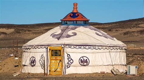 A Yurt In The Desert With An Orange Door And Window On Its Side