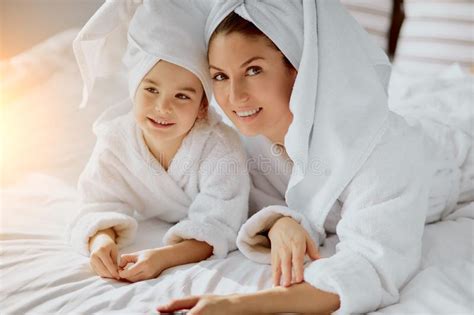 Happy Mother And Daughter Tidy Up After Shower Together On Bed Stock