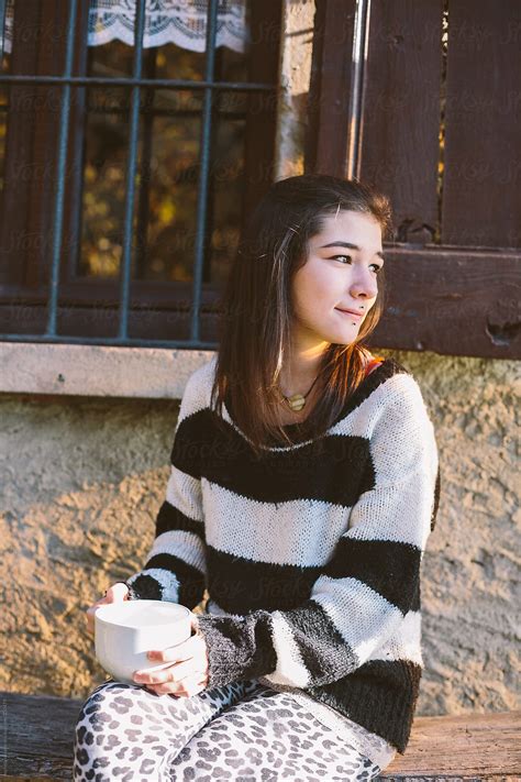 Cute Girl Drinking A Cup Of Tea Sitting Outdoors Del Colaborador De Stocksy Michela Ravasio