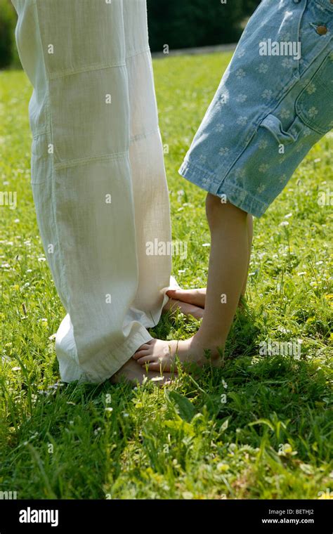 Close Up Of A Mothers And Daughters Legs With The Daughters Bare Feet On Top Of The Mothers