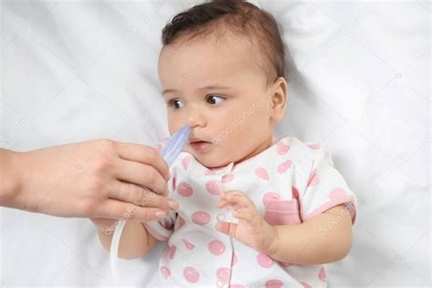Madre Usando Un Aspirador Nasal Para Un Bebé Pequeño Y Lindo Acostado