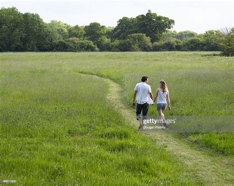 Young Couple Walking Through Meadow Hand In Hand Stock Photo Getty Images