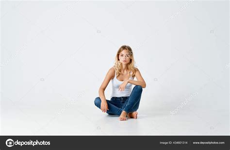 Women Legs Crossed Sitting On The Floor Indoors In Jeans And T Shirt