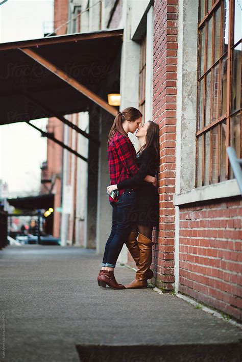 Lesbian Couple Embrace Against Brick Wall During A Date Downtown By Kate Daigneault Stocksy United