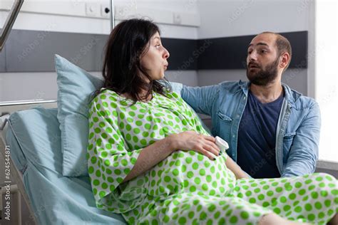 Pregnant Woman Going Into Labor In Hospital Ward Husband Standing