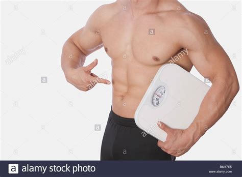 Mid Section View Of A Man Holding A Bathroom Scale And Showing His